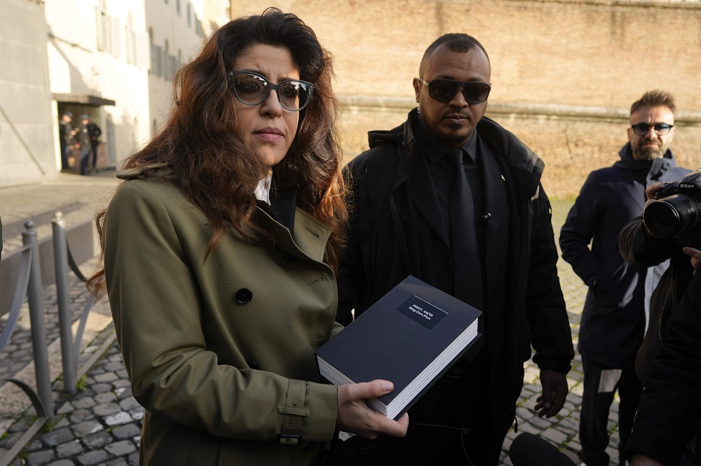 Public relations specialist Francesca Chaouqui, previously financial consultant for the Vatican, shows reporters documents, as she arrives for testimony in a trial in the city-state's criminal tribunal, Friday, Jan. 13, 2023.