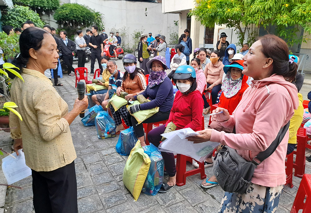 Sacred Heart of Jesus Sr. Mary Nguyen Thi Phuc, left, offers rice, fish sauce and cooking oil to people Jan. 12 in Nha Trang. (GSR photo/Joachim Pham)