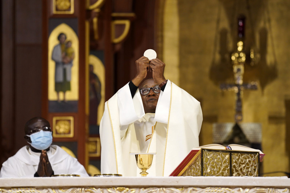 Fr. Eden Jean Baptiste elevates the Eucharist as he celebrates a Mass for Catholics of Haitian ancestry at St. Agnes Cathedral in Rockville Centre, New York, Jan. 1, 2022, the feast of Mary, Mother of God. (CNS/Gregory A. Shemitz)