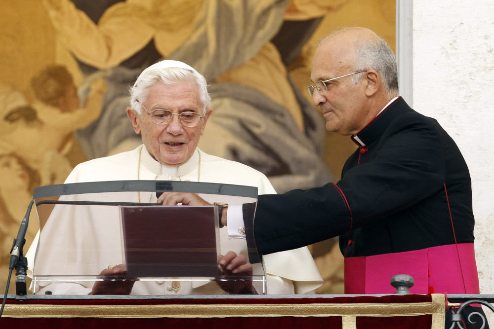 Pope Benedict XVI is assisted by his assistant personal secretary, then-Msgr. Alfred Xuereb, as he prepares to lead the Angelus from a window at the papal summer residence in Castel Gandolfo, Italy, in August 2012. (CNS photo/Giampiero Sposito, Reuters) 