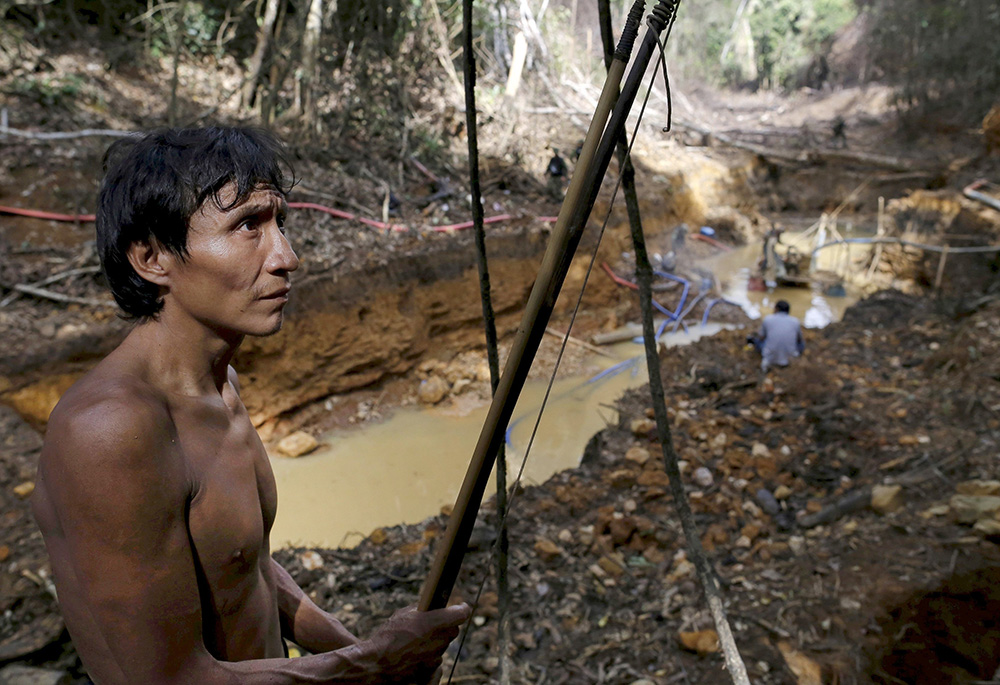 A Yanomami man is pictured in a 2019 photo standing near an illegal gold mine on Indigenous land in the heart of Brazil's Amazon rainforest. (CNS/Reuters/Bruno Kelly)