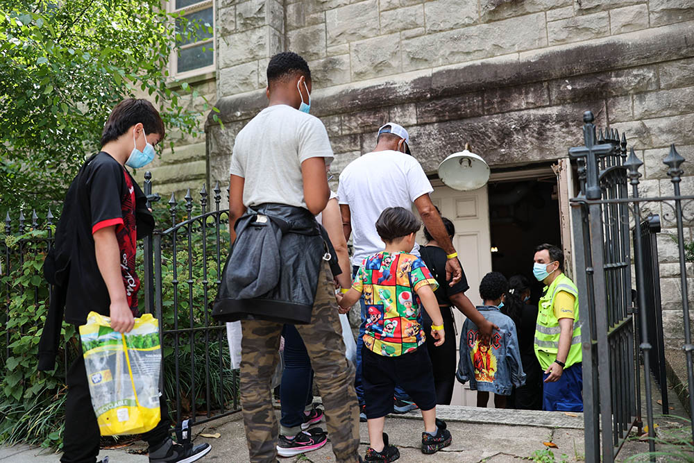 Migrants who arrived on a bus from Arizona step into the parish hall at St. Peter's Church on Capitol Hill in Washington Aug. 5, 2022. The local church, partnering with SAMU First Response, began offering hospitality in late July to migrants arriving on buses sent to Washington by the governors of Texas and Arizona. (CNS/Catholic Standard/Andrew Biraj)