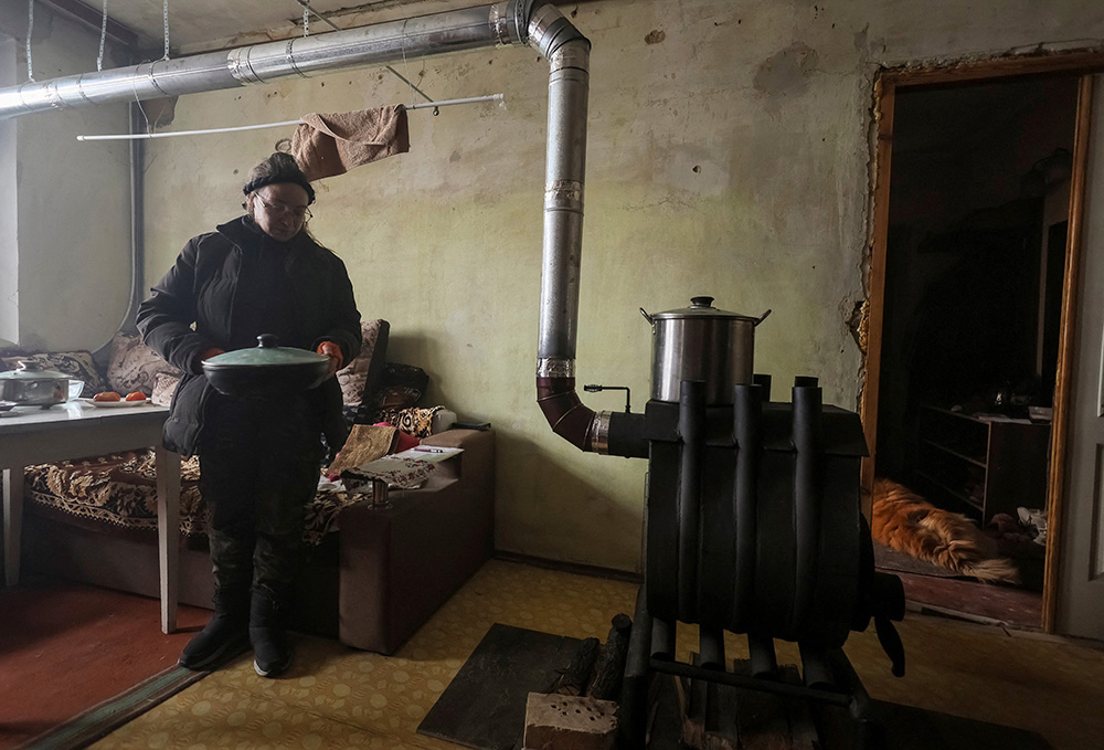Local resident Tetiana Reznychenko prepares food at a wood stove installed in her flat, which has no electricity, heating and water, on the fifth floor of an apartment building destroyed by a Russian military strike Horenka, Ukraine, in this photo taken Nov. 19, 2022. (CNS/Reuters/Gleb Garanich)