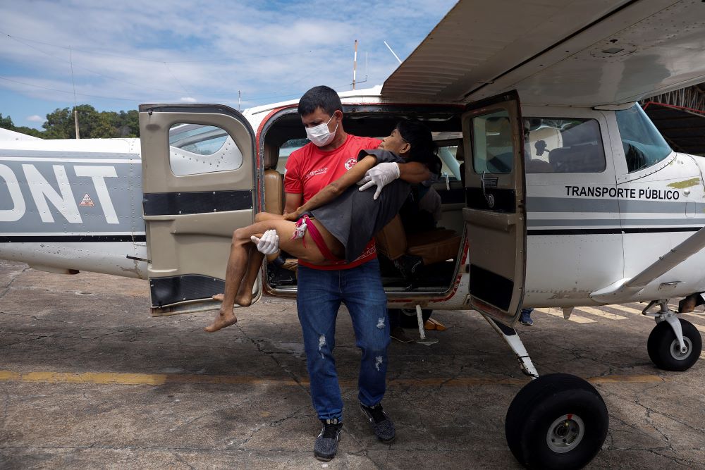 A health worker carries a Yanomami woman suffering from malaria, who was removed from indigenous land, as she leaves the airplane to be treated in Boa Vista, Brazil, Jan. 29, 2023. (OSV News/Reuters/Amanda Perobelli)