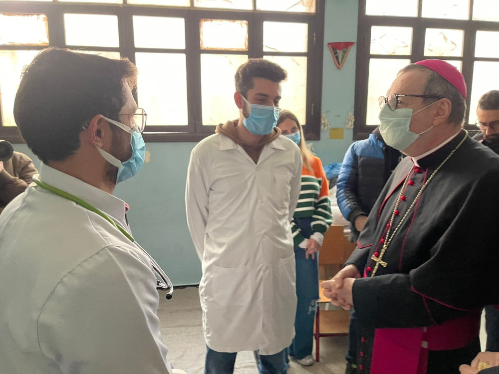 A masked archbishop talks to two Turkish doctors with white coats and masks