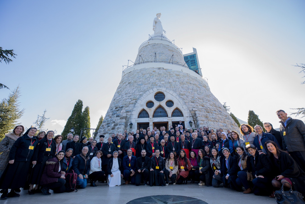 A large group, including women religious, takes a picture outside a chapel