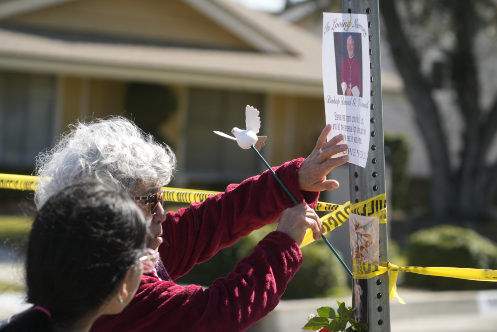 Rosa Maria Perez, with her granddaughter Abigail Gil, pay their respects to Bishop David O'Connell at the corner of his home in Hacienda Heights, California, Feb. 19. According to the Los Angeles County Sheriff's Department, detectives are investigating the death of O'Connell, who was shot and killed Saturday just blocks from a church, as a homicide. (AP/Damian Dovarganes)