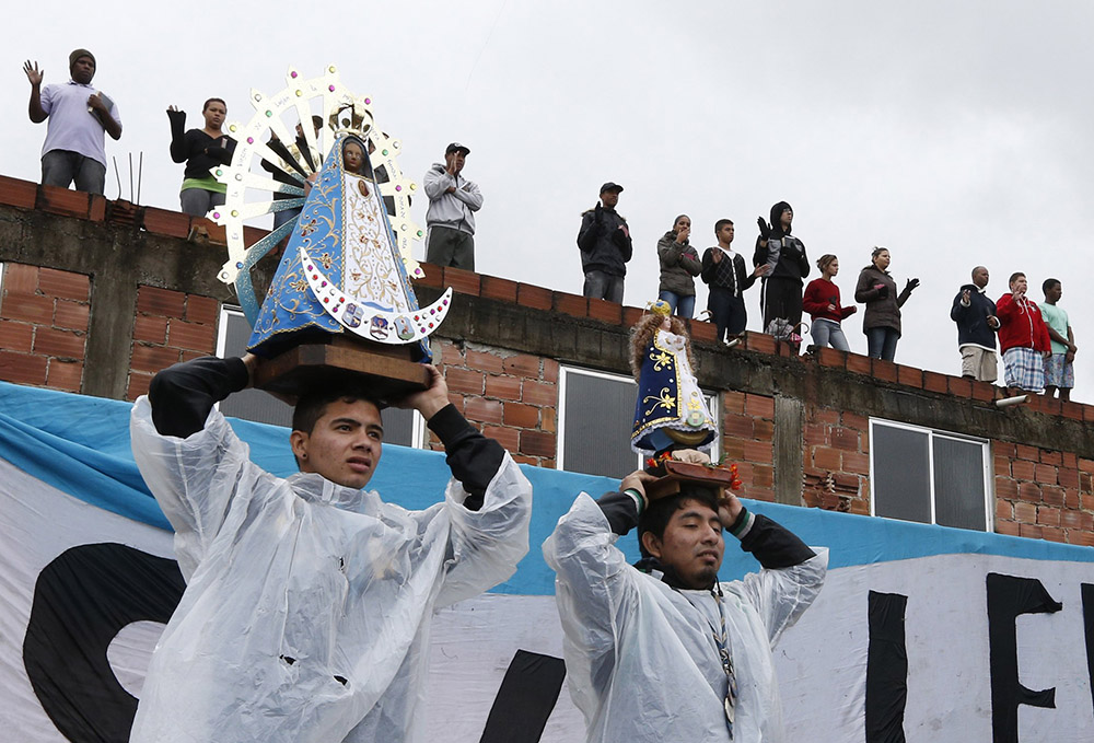 Residents hold statues of Our Lady of Aparecida as Pope Francis visits the Varginha slum in Rio de Janeiro July 25, 2013, during his weeklong visit to Brazil for World Youth Day. (CNS/Paul Haring)