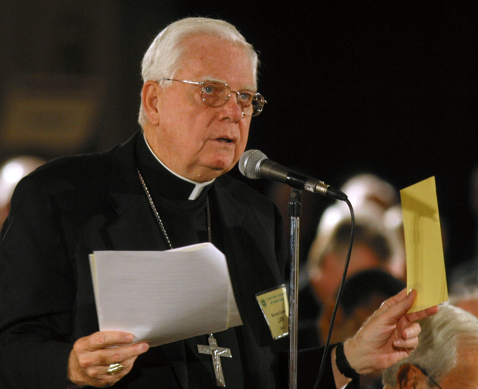 Cardinal Bernard Law holds papers and speaks at meeting of bishops.