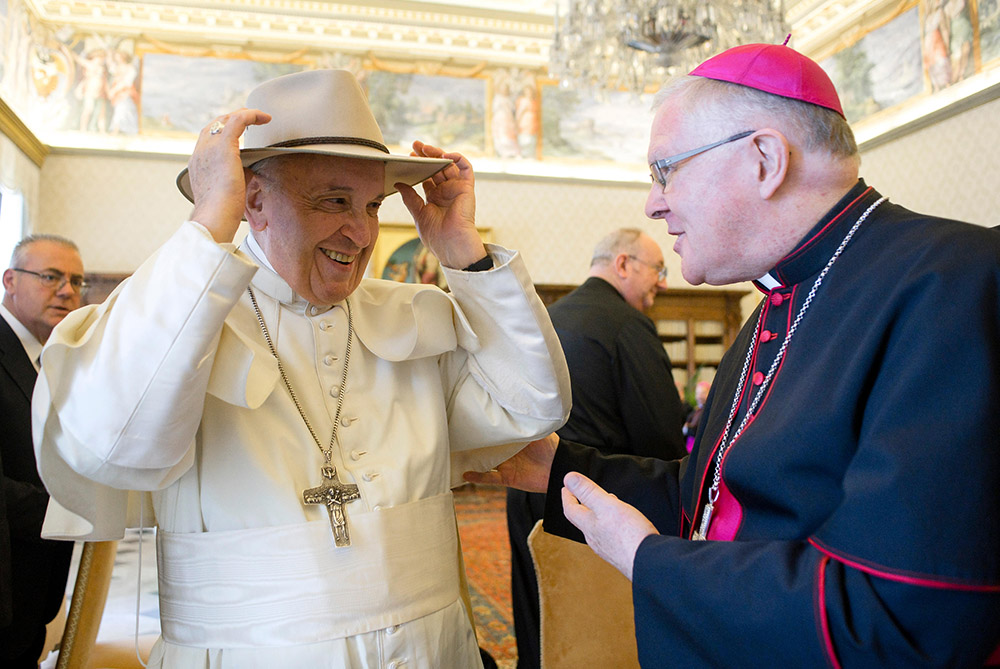 Pope Francis tries on a hat presented by Archbishop Mark Coleridge of Brisbane during a meeting with Australian bishops at the Vatican June 24, 2019. (CNS/Vatican Media)