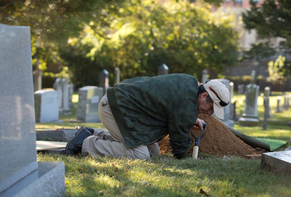 A church employee at St. Mary Catholic Church in Alexandria, Va., prepares an urn burial at the parish's cemetery in this 2017 file photo. (CNS photo/Tyler Orsburn)