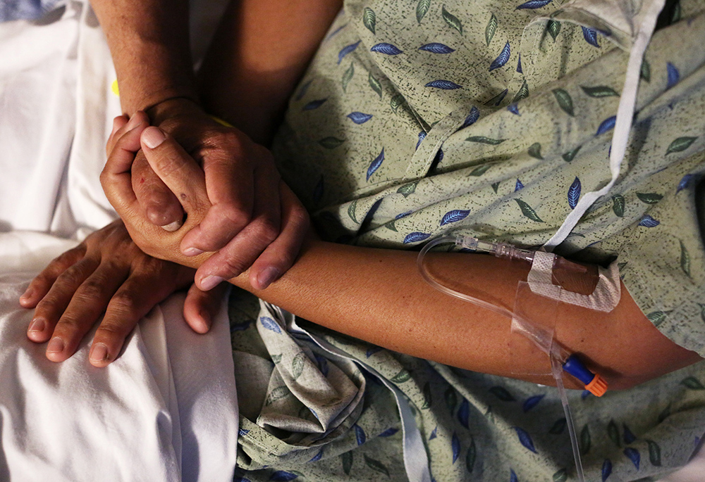 A hospital patient is comforted by a family member in this illustration photo. The U.S. Catholic bishops issued a document dated March 20 rejecting gender-affirming medical treatments for transgender individuals and reasserting that such procedures must not be performed by Catholic providers. (CNS/Reuters/Caitlin O'Hara)