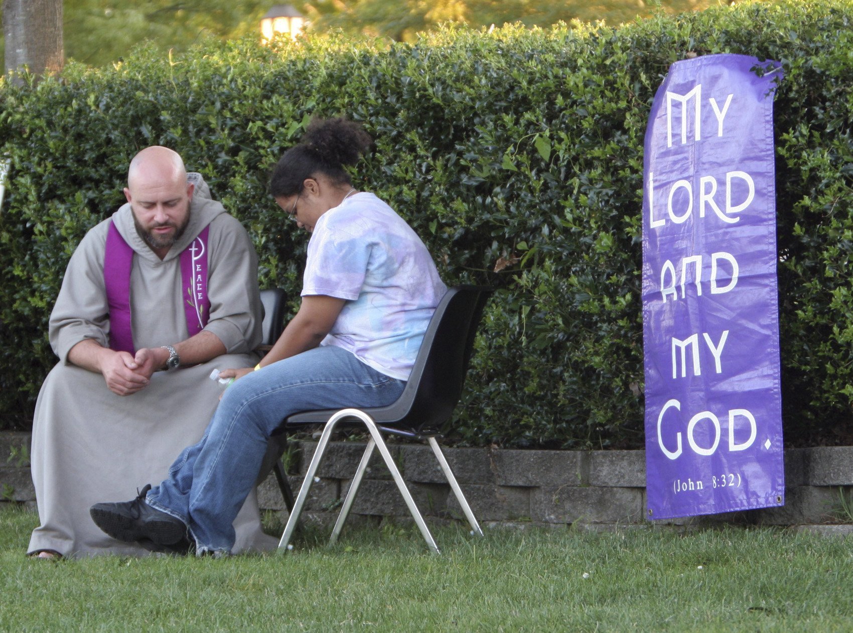 Priest and young person on chairs outside during penance 