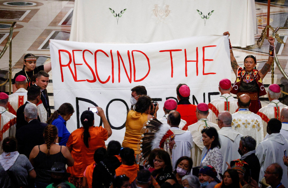 Indigenous people hold a banner calling on Pope Francis to "rescind the doctrine," an apparent reference to the so-called Doctrine of Discovery, during a papal Mass at the National Shrine of Sainte-Anne-de-Beaupré July 28, 2022, in Quebec. (CNS/Reuters/Guglielmo Mangiapane)