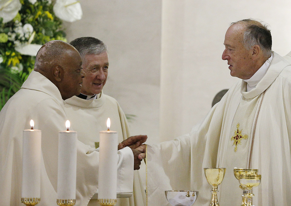 From left, Cardinals Wilton Gregory of Washington, Blase Cupich of Chicago and Robert McElroy of San Diego exchange the sign of peace during Mass at St. Patrick's Church, official home of the U.S. Catholic community in Rome, on Aug. 28, 2022. (CNS/Paul Haring)