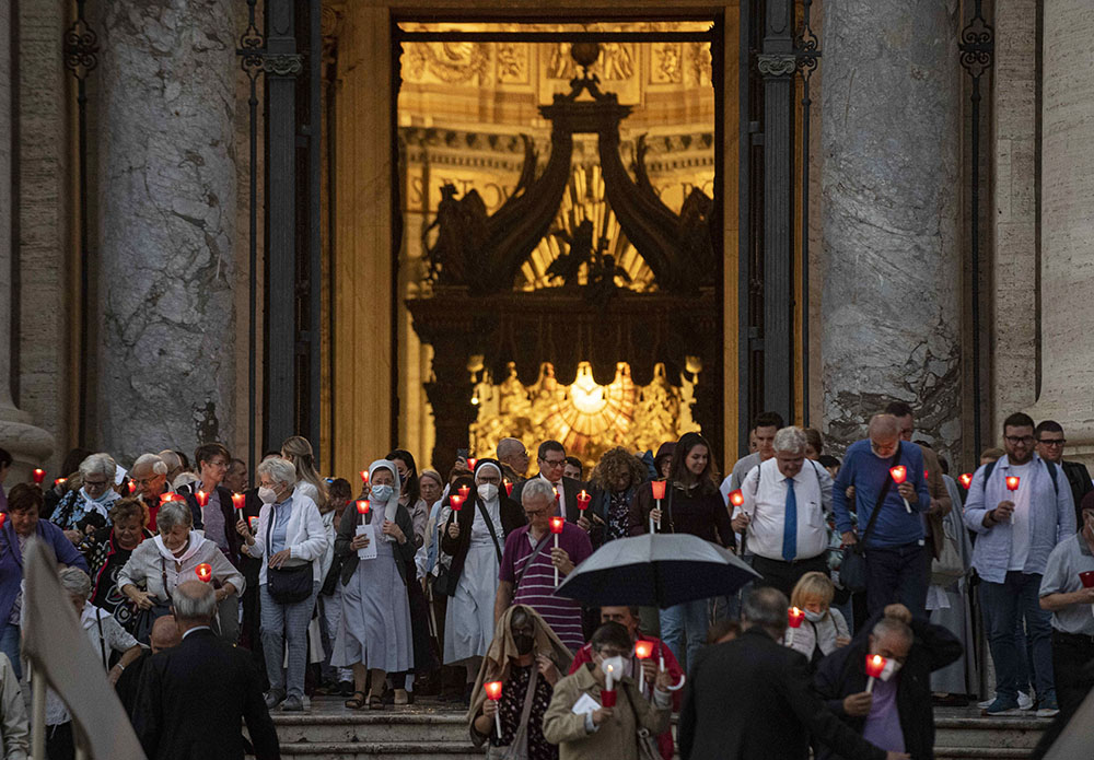 People holding lighted candles leave St. Peter's Basilica after Pope Francis celebrated Mass Oct. 11, 2022, to mark the 60th anniversary of the opening of the Second Vatican Council. (CNS photo/Vatican Media)