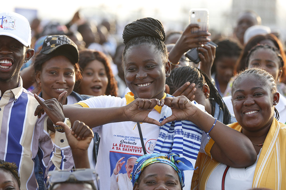A young woman gestures in the shape of a heart as people wait for the start of Pope Francis' celebration of Mass at Ndolo airport in Kinshasa, Congo, Feb. 1, 2023. (CNS/Paul Haring)