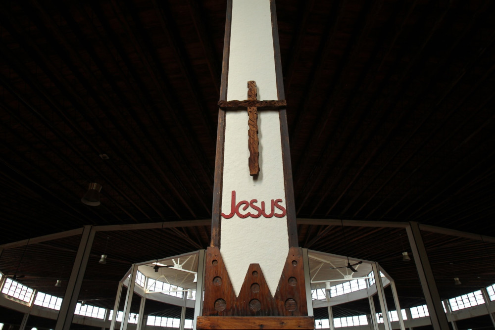 A cross with the word Jesus under it stands on a white pole