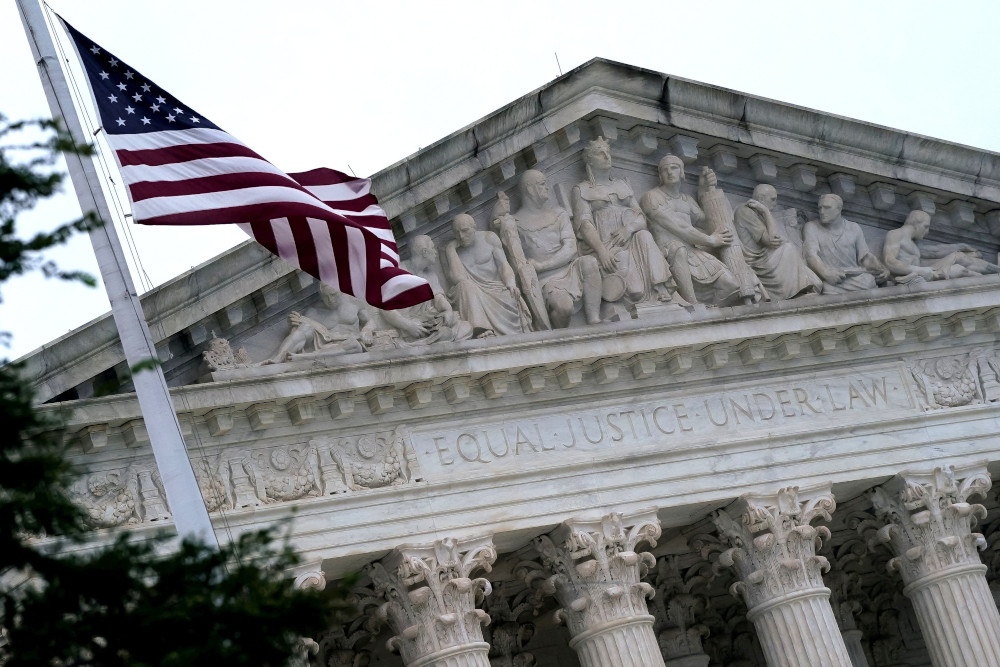 The top of the Supreme Court building with an American flag, the upper parts of the columns, and the roof