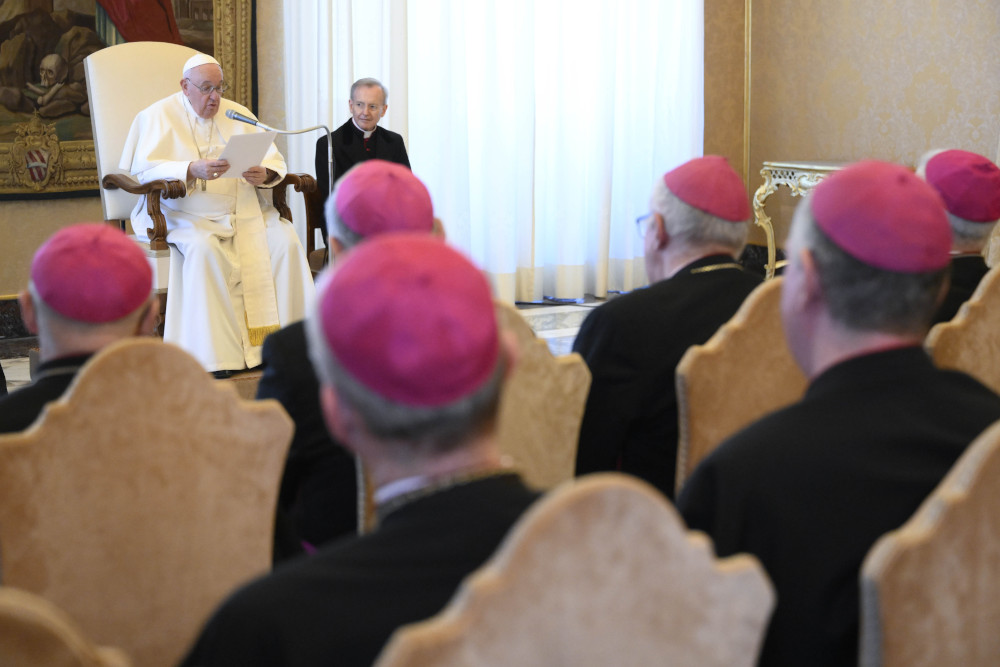 A sea of men in violet zucchettos sits in front of Pope Francis and a man in a black cassock with not zucchetto