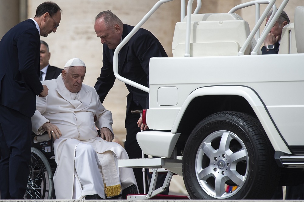 Pope Francis is assisted at the end of his general audience in leaving St. Peter's Square March 29 at the Vatican. The pope was hospitalized that afternoon with a respiratory infection but is gradually improving, the Vatican said March 30. (OSV News/Antoine Mekary)