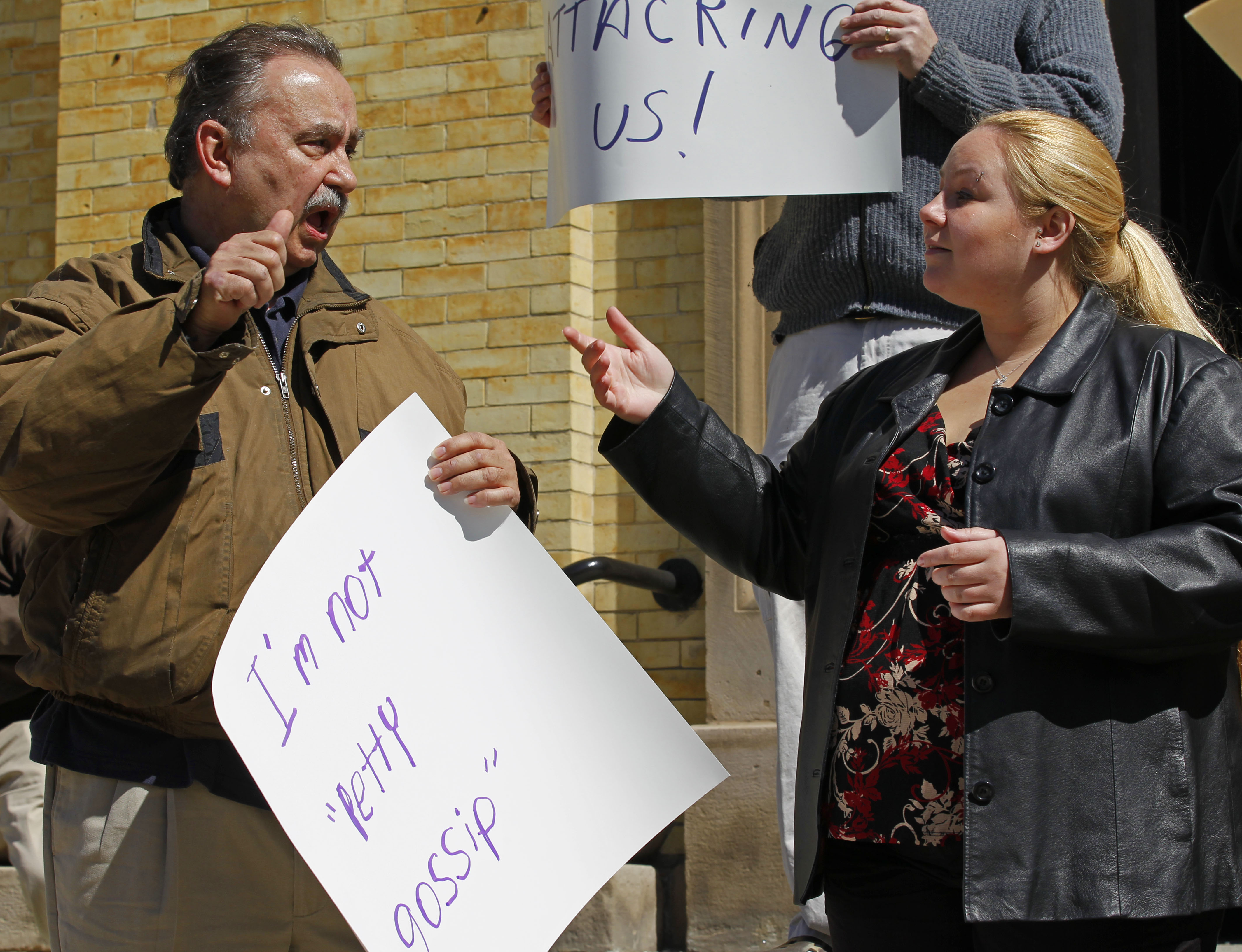 Man speaks at protest while daughter signs for him. 