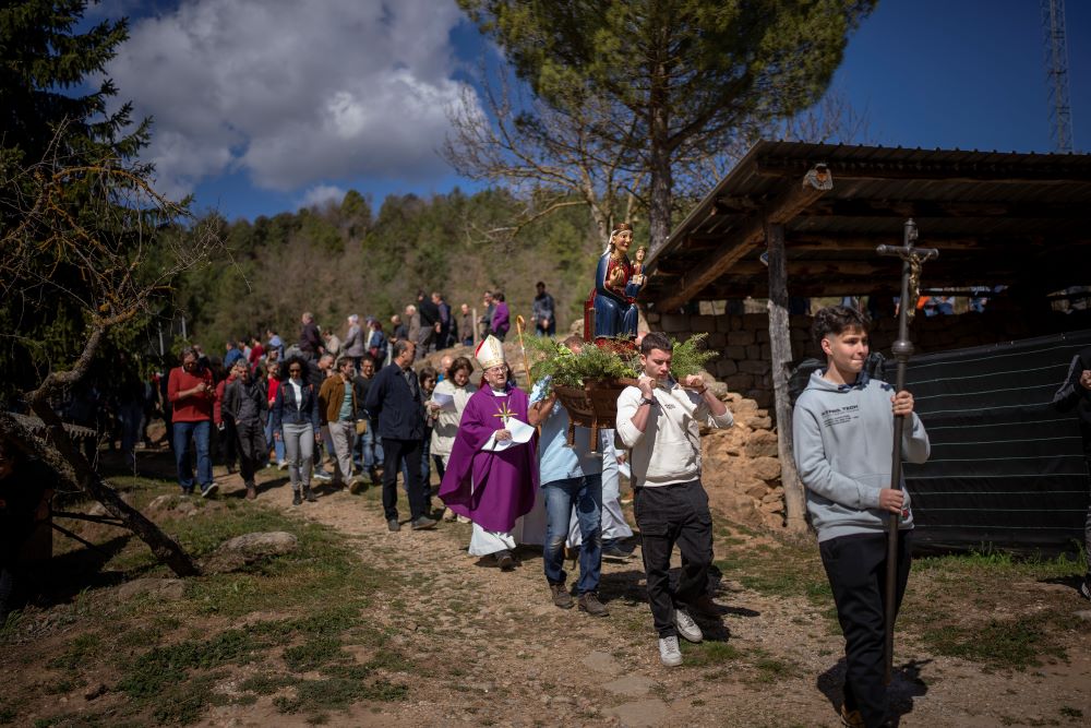 Local residents take part in a procession carrying a replica of the Our Lady of the Torrents, a virgin historically associated with drought, in l'Espunyola, north of Barcelona, Spain, Sunday, March 26, 2023. (AP Photo/Emilio Morenatti)