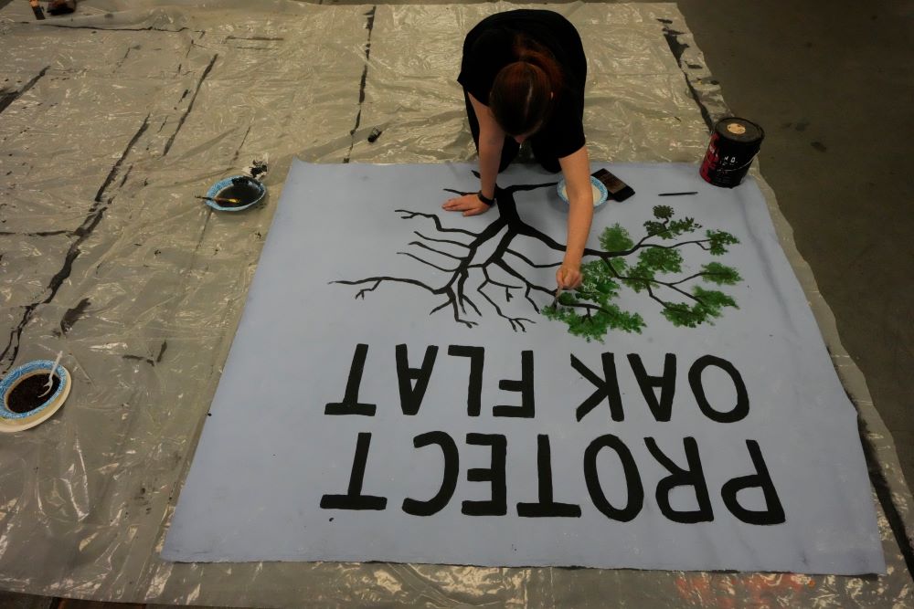 A member of the Apache Stronghold group who traveled from Arizona paints a protest banner at Self Help Graphics & Art in the Los Angeles neighborhood of Boyle Heights on Monday, March 20, 2023.