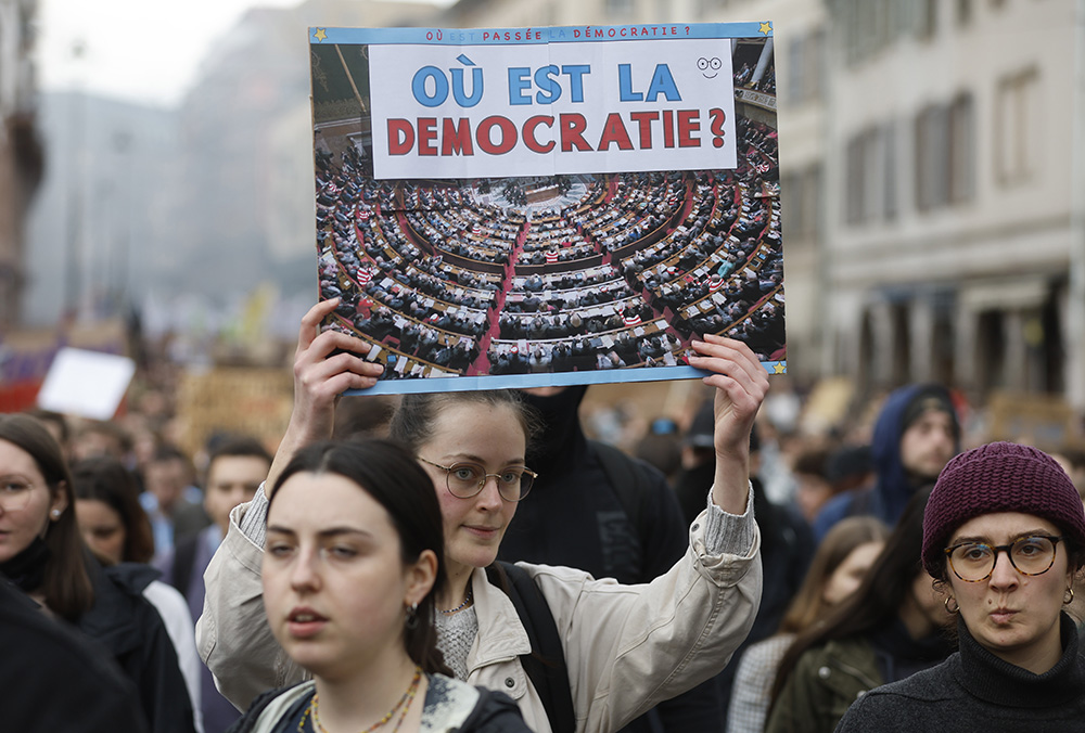 A protester holds a placard that reads, "Where is democracy?", during a rally in Strasbourg, France, March 23. French unions are holding mass demonstrations after President Emmanuel Macron enflamed public anger by forcing a higher retirement age through parliament without a vote. (AP/Jean-Francois Badias)