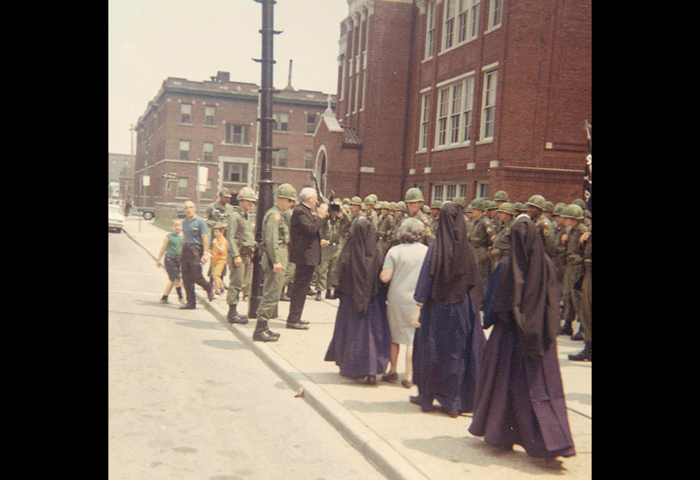 Then-Archbishop John Dearden of Detroit talks with troops stationed outside St. Rose of Lima Church on Detroit's east side as a group of Catholic sisters listens nearby during the 1967 unrest. Dearden launched a three-year synodal process that took place in Detroit, culminating in its 1969 diocesan synod. (CNS/Archdiocese of Detroit Archives)