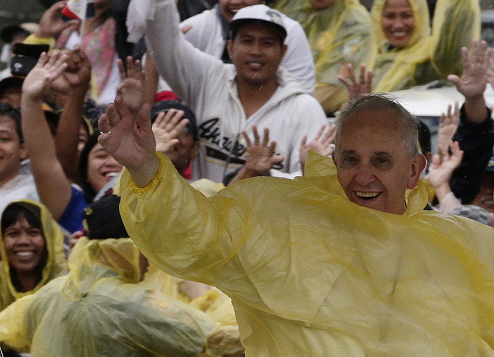 Pope Francis arrives in Tacloban City, the Philippines, on Jan. 17, 2015, as a rain-drenched but lively crowd wearing yellow and white raincoats welcomes him to the typhoon-ravaged city. (AP/Bullit Marquez)
