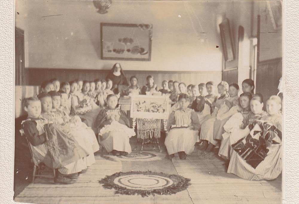 Female students show their handiwork at St. Benedict's Mission School on the White Earth Indian Reservation in Minnesota in the 1890s. ("Work room at St. Benedict's Mission School," College of Saint Benedict/Saint John's University Libraries, https://csbsjulib.omeka.net/items/show/928)