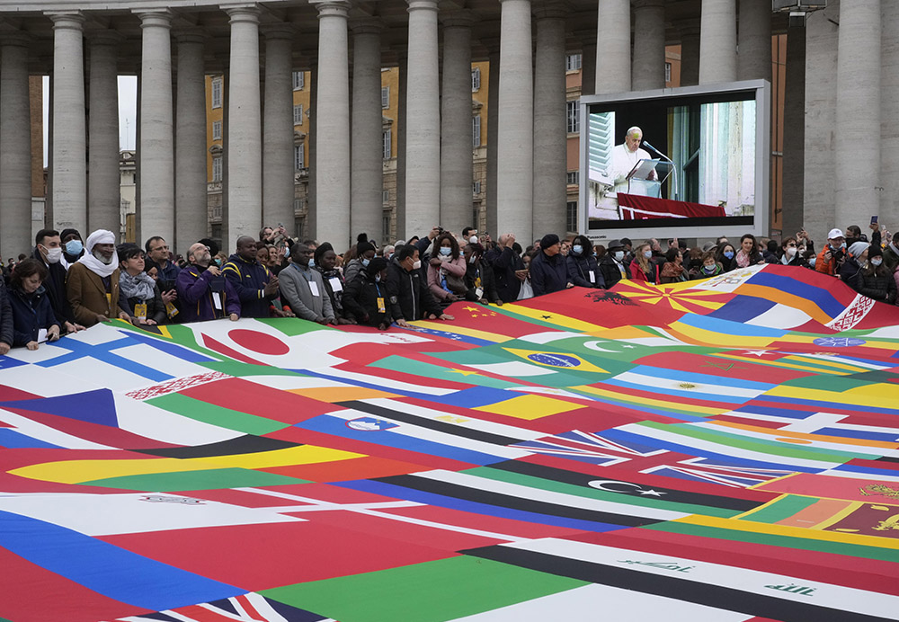 Members of a migrants association hold a huge banner made with the world's flags as Pope Francis delivers the Angelus prayer in St. Peter's Square at the Vatican Nov. 28, 2021. (AP/Gregorio Borgia)