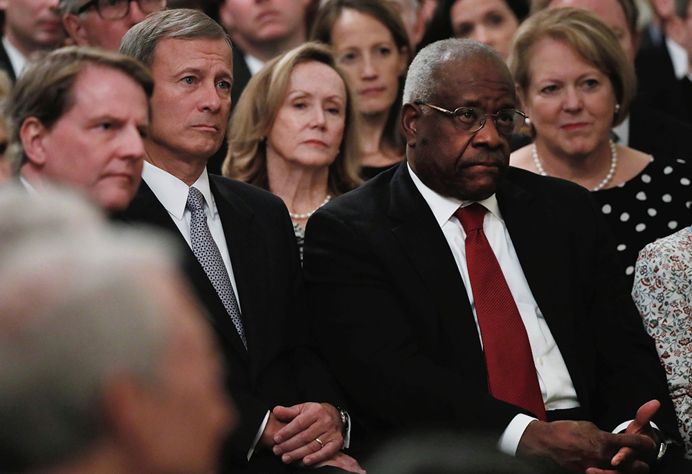 U.S. Supreme Court Chief Justice John Roberts, second from left, and Justice Clarence Thomas, both Catholic, listen during the public swearing-in ceremony for Justice Brett Kavanaugh Oct. 8, 2018, in the East Room of the White House in Washington. Kavanaugh, a Catholic, replaced Justice Anthony Kennedy, also a Catholic, who retired July 31, 2018. (CNS/Reuters/Jonathan Ernst)