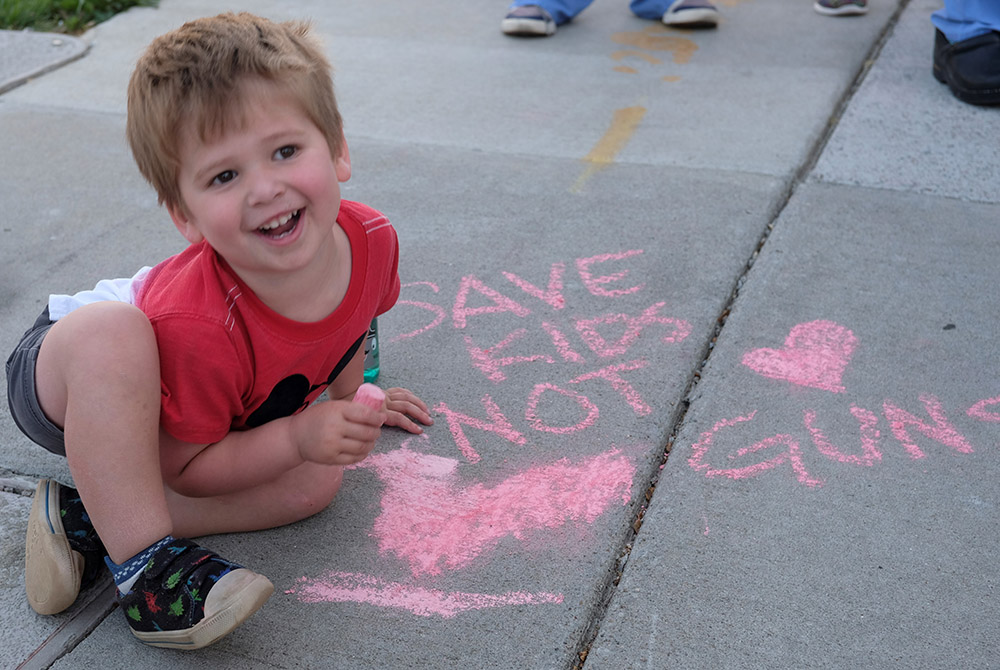 A 3-year-old boy plays with chalk as people gather for an event outside the Tennessee Capitol in Nashville April 18 to push the Legislature to address gun violence. (OSV News/Tennessee Registe/Katie Peterson)