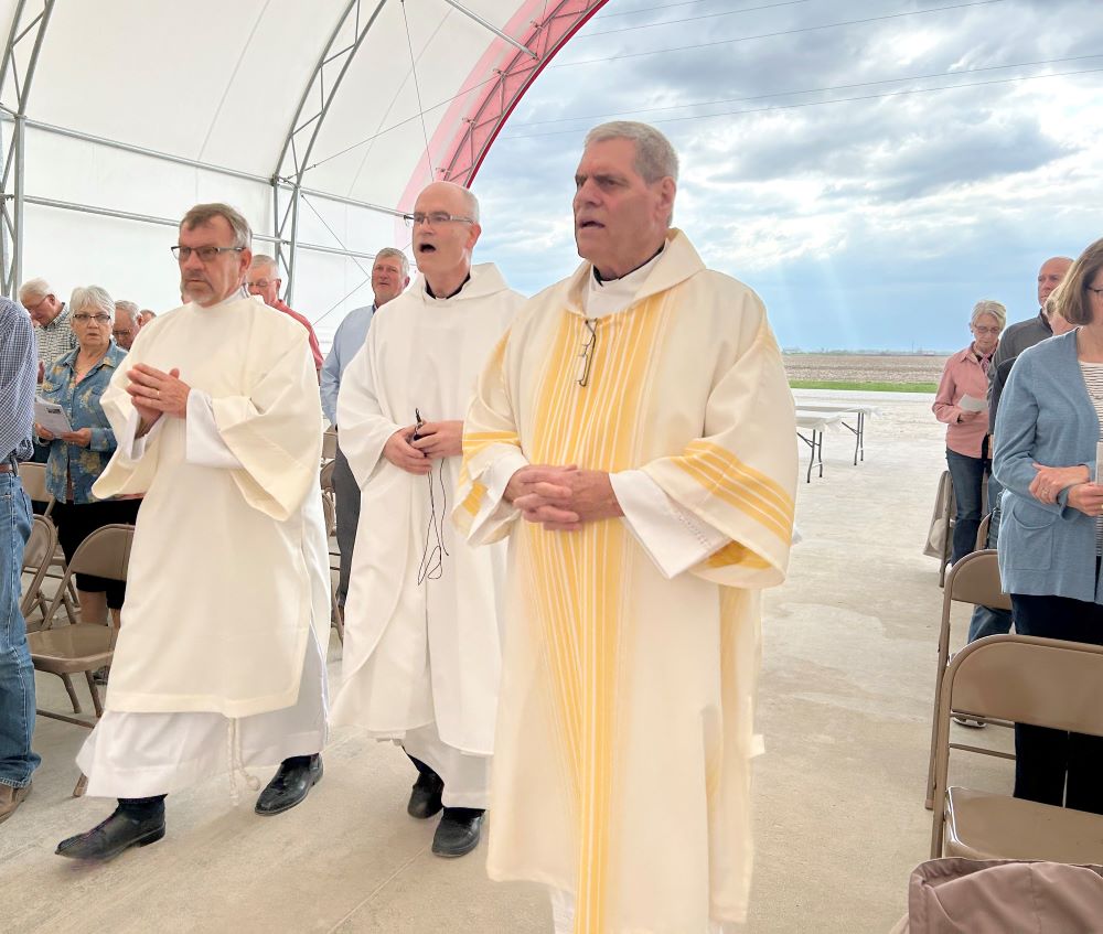 Deacon Mike Linnenbrink, Fr. Dan Dorau and Deacon Dan Freeman process to the altar April 15, 2023, during a Mass on the farm and the blessing of seeds in the barn on the Pieper family farm in Donnellson, Iowa. (OSV News/The Catholic Messenger/Barb Arland-Fye)