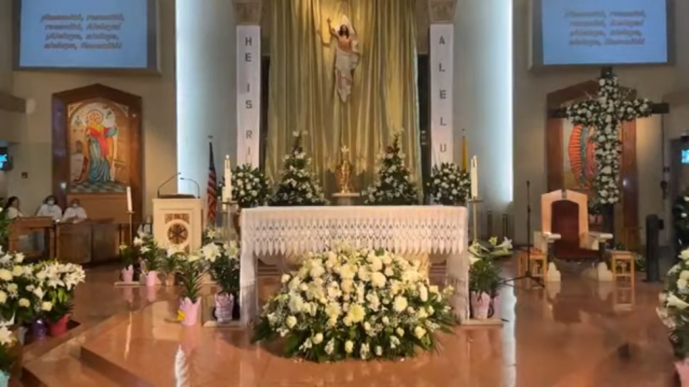 The altar at St. Emydius Roman Church in Los Angeles County, California, is dressed with flowers for Easter. At right, a flower-covered cross stands in front of an image of Our Lady of Guadalupe. (NCR Photo/YouTube)