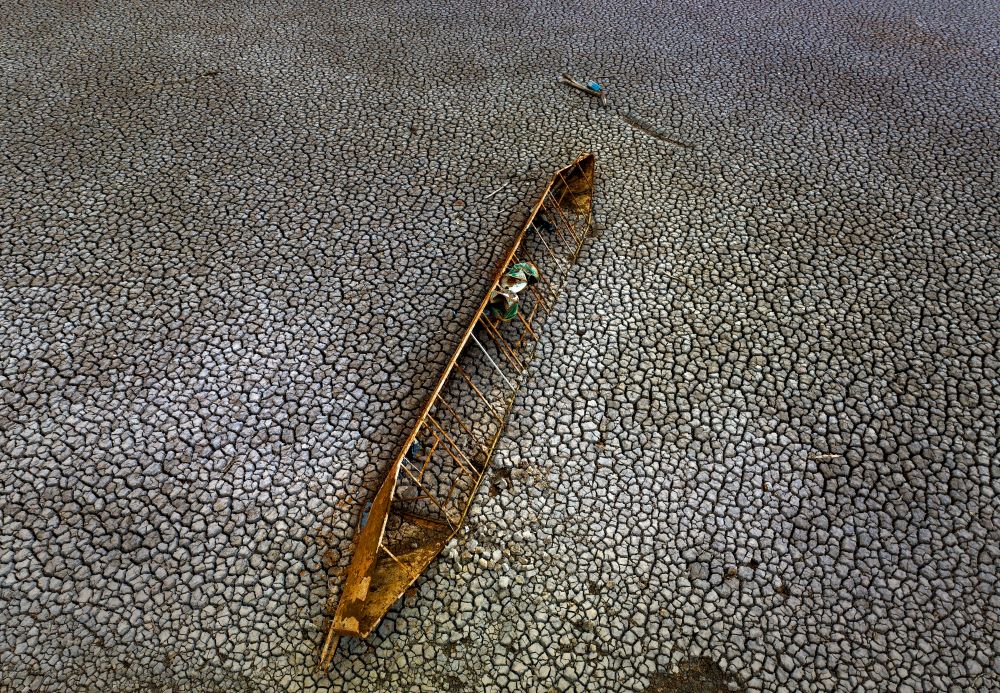 An old boat is photographed half-buried after the water level has dropped at the Sau reservoir, about 100 km (62 miles) north of Barcelona, Spain, Tuesday, April 18, 2023. (AP Photo/Emilio Morenatti)