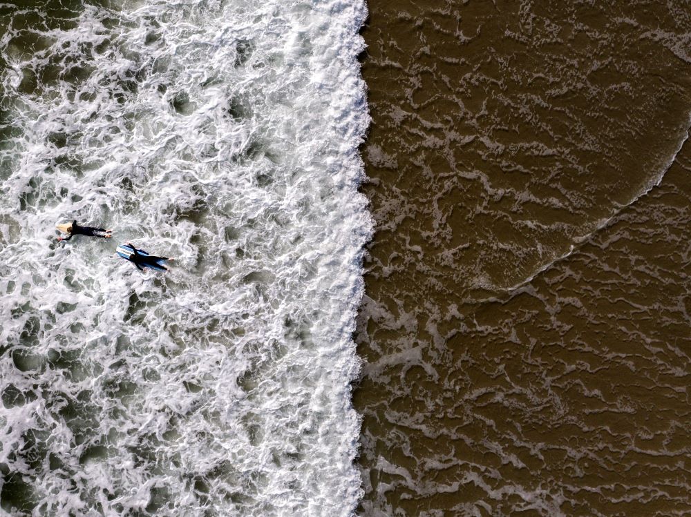 Two surfers wade through water in Huntington Beach, Calif., Monday, April 17, 2023. (AP Photo/Jae C. Hong)