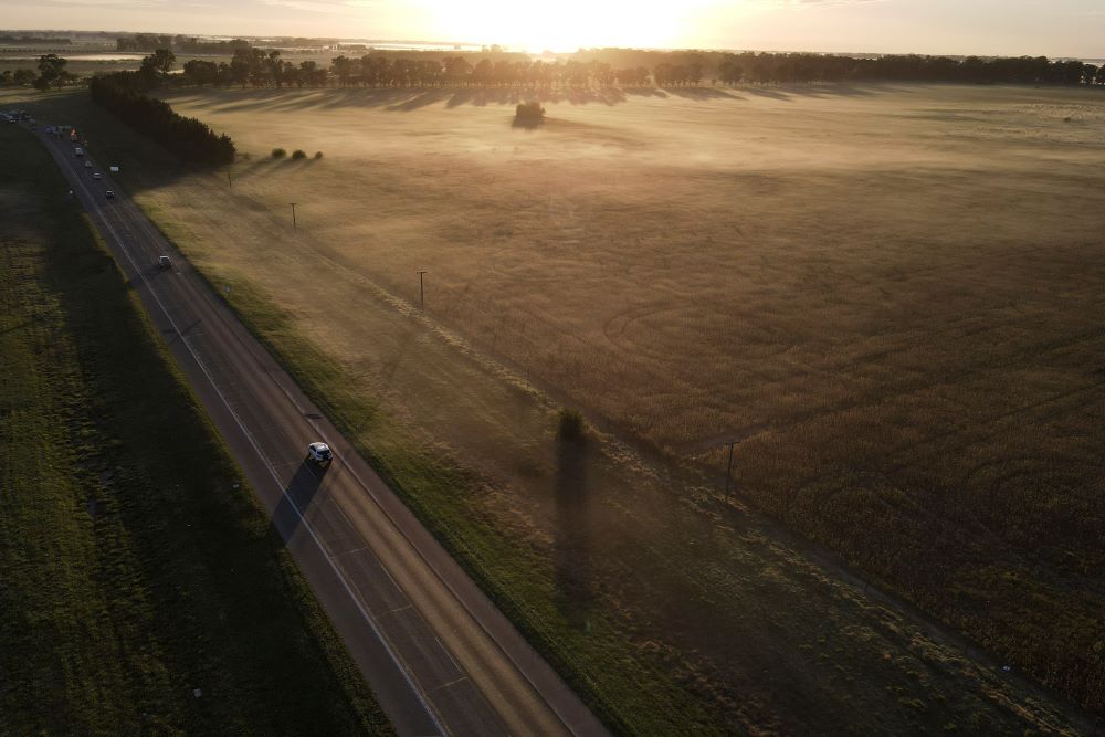 A car drives down a road near farmland in Lobos, Argentina, Friday, April 14, 2023. Huge amount of the harvest of soybean and corn has been lost in Argentina due to drought. (AP Photo/Natacha Pisarenko)