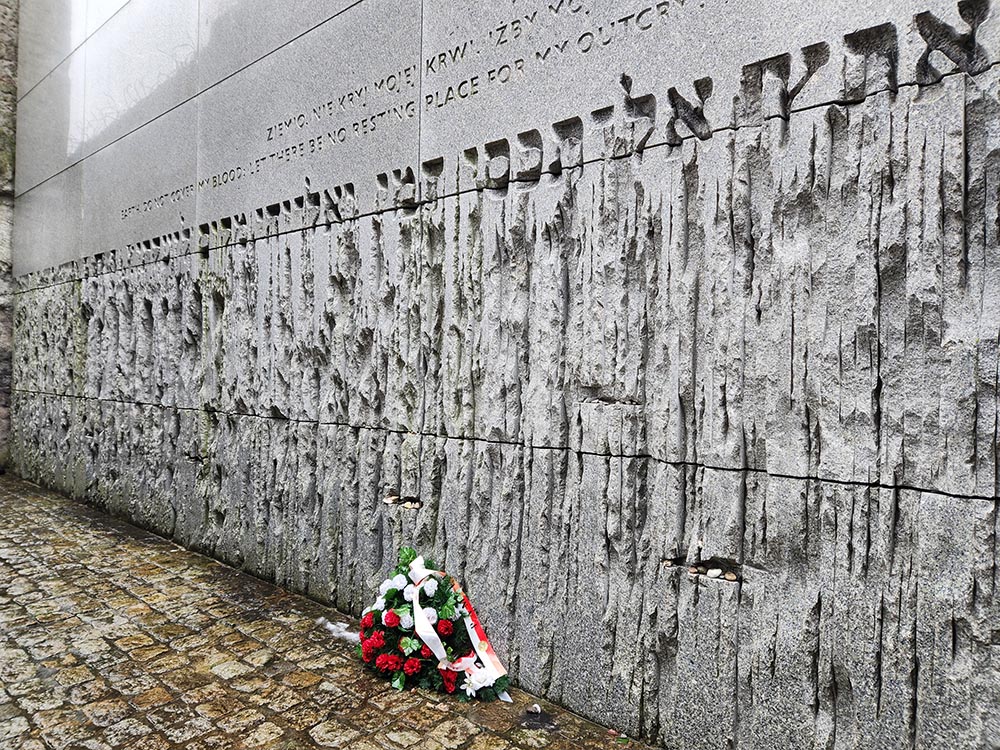 At Bełżec in Poland, a 60-foot-high wall with an engraving, in English, Hebrew and Polish, of Job 16:18: "Earth, do not cover my blood; let there be no resting place for my outcry!" (NCR photo/Chris Herlinger)