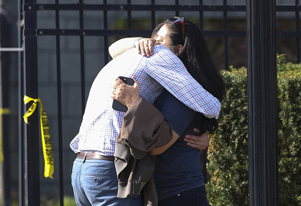 Two people embrace outside of a building where a shooting took place April 10 in Louisville, Kentucky. (Michael Clevenger/Courier Journal via AP)