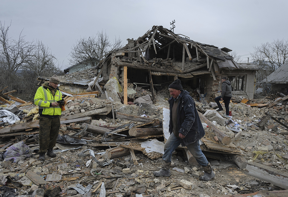 Villagers walk in the debris of private houses ruined in Russia's night rocket attack in a village, in Zolochevsky district in the Lviv region, Ukraine, March 9. NCR board member David Bonior and contributor Fr. Peter Daly traveled to Ukraine and Poland in March. (AP photo/Mykola Tys)
