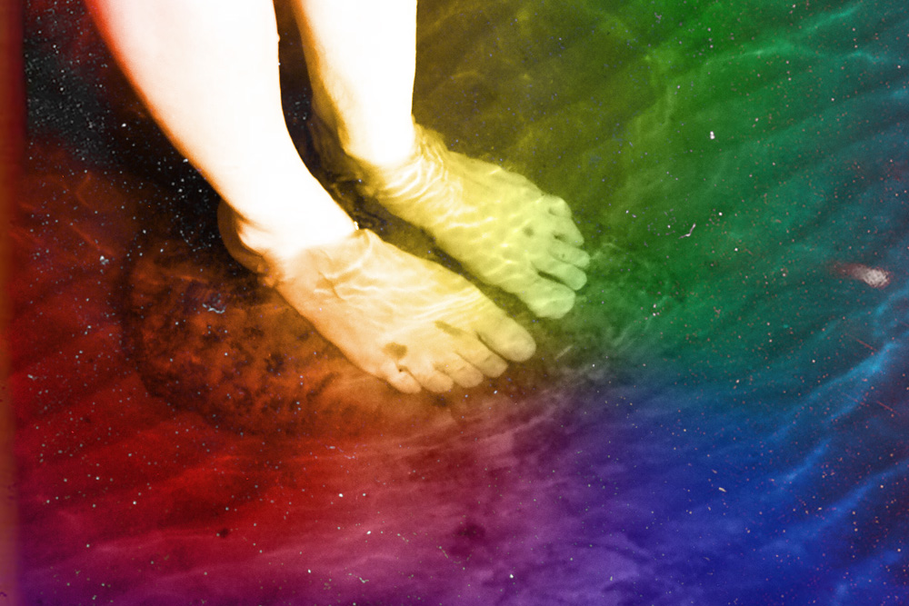 Feet standing in water with a rainbow hue (Maxwell Kuzma)