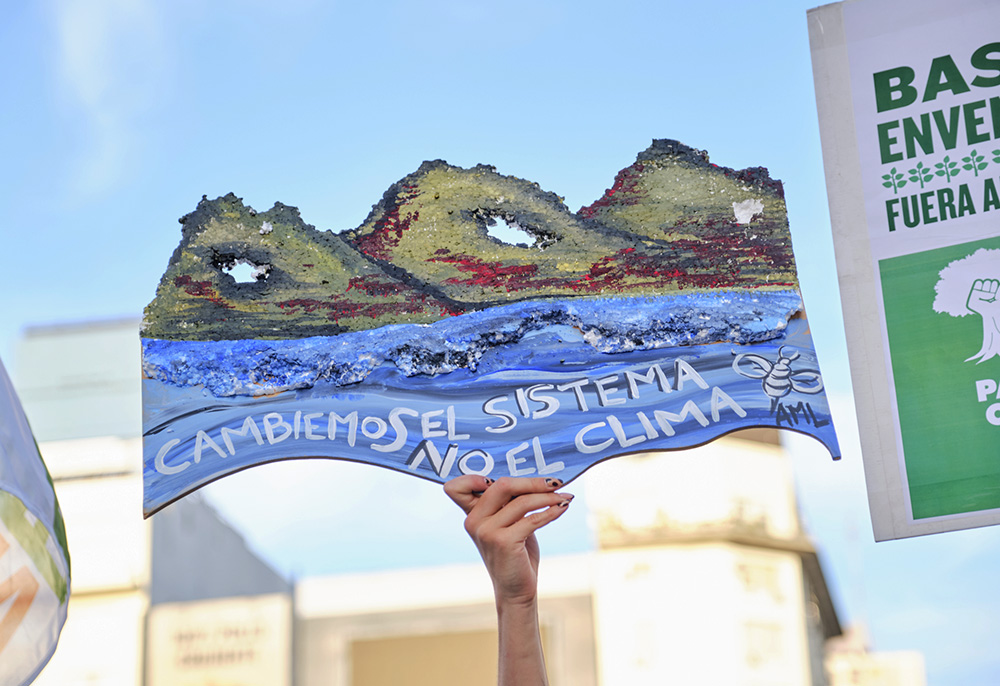 A protester holds up a sign saying in Spanish, "Let's change the system, not the climate," during a climate strike in Buenos Aires, Argentina, March 3. (Dreamstime/Carolina Jaramillo)