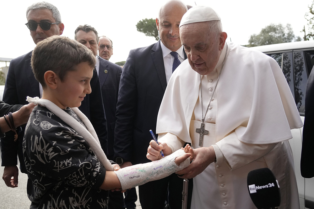 Pope Francis signs a boy's arm cast