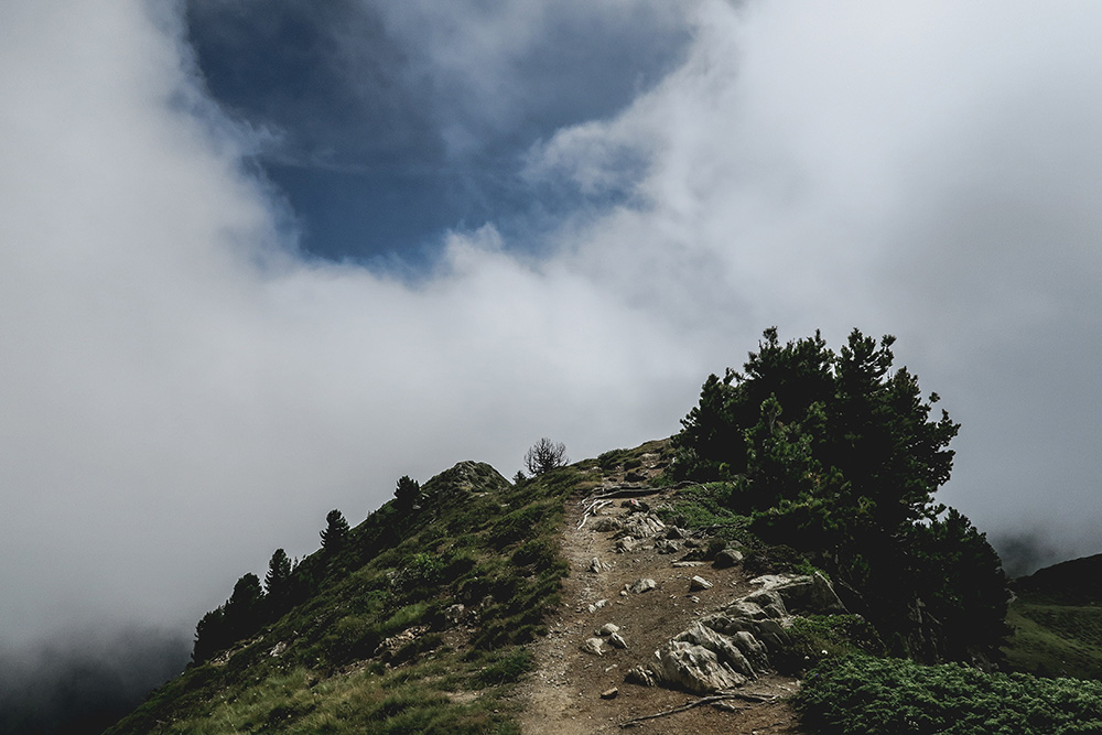 A hilltop with an opening in the clouds above it (Unsplash/Paul Pastourmatzis)