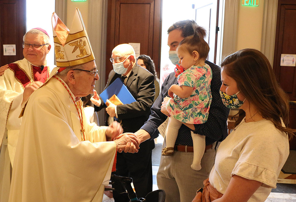 Cardinal Justin Rigali, retired archbishop of Philadelphia, greets parishioners at the Cathedral of the Most Sacred Heart of Jesus in Knoxville, Tennessee, after a Mass marking the 60th anniversary of his priestly ordination April 25, 2021. At left is Knoxville Bishop Richard Stika. Since his retirement in 2011, Cardinal Rigali has been in residence with Bishop Stika. (CNS/The East Tennessee Catholic/Bill Brewer)