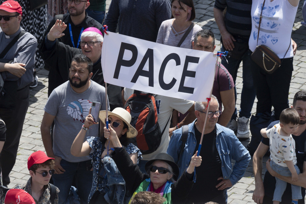 People hold up a sign saying, "Peace," as they join Pope Francis for the midday recitation of the "Regina Coeli" prayer in St. Peter's Square at the Vatican May 21, 2023. (CNS photo/Vatican Media)