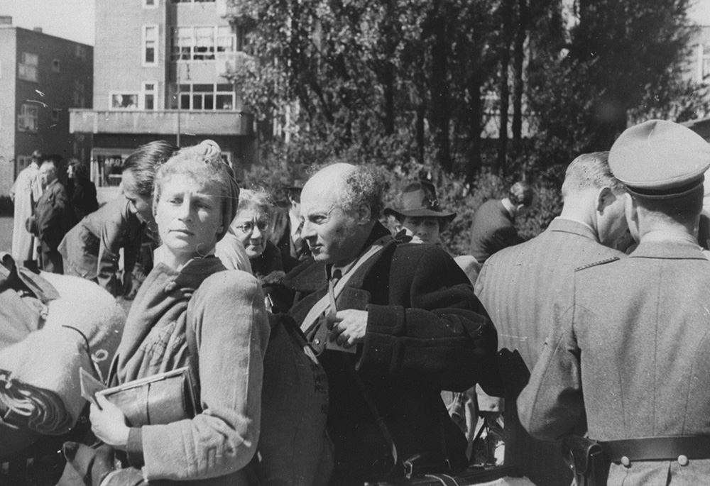 Amsterdam Jews await deportation to the Nazi transit camp in Westerbork, the Netherlands, on June 20, 1943. A member of the German Security Police can be seen at right. (Wikimedia Commons/Netwerk Oorlogsbronnen/Herman Heukels)